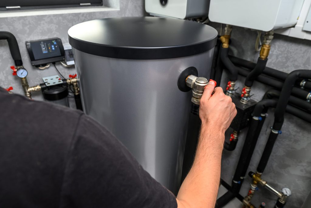 Plumber adjusts valve on boiler.