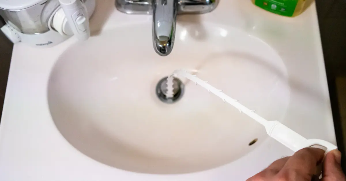 Plumber shows debris on drain tool.