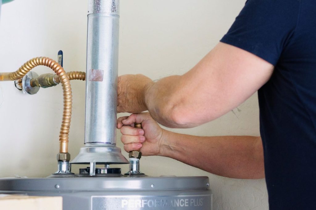 Person tightening water heater bolt.